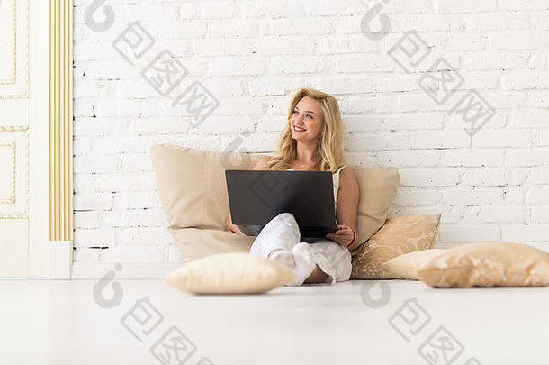 年轻的金发女郎女人坐地板上枕头移动PC电脑美丽的女孩快乐微笑