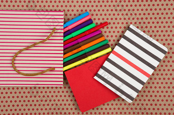 教育和庆祝概念-手工条纹购物袋、礼品袋、办公桌配件、彩色毡尖笔、cra上的红色和条纹记事本