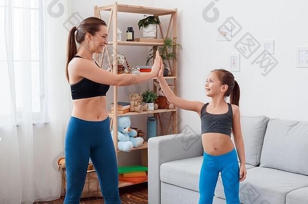 健康的生活方式妈妈。女儿运动服装站锻炼显示肱二头肌微笑惊讶强大的