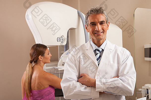 微笑的男医生和40多岁的妇女正在接受乳房X光扫描。