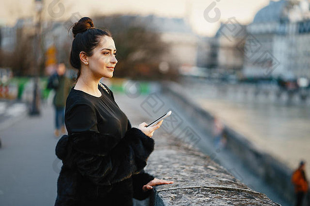 一名女子在巴黎行走时使用手机