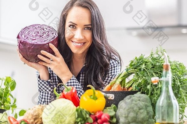 在厨房里拿着新鲜的红色卷心菜的顽皮的年轻女子——节食蔬菜和健康概念。