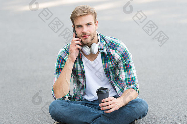 重要电话。电话。听音乐。电子书概念。男式格子衬衫。学生<strong>放</strong>松和充电。咖啡带走。那个家伙在户外喝咖啡。那个人坐在地上。戴着耳机的无忧无虑的学生。
