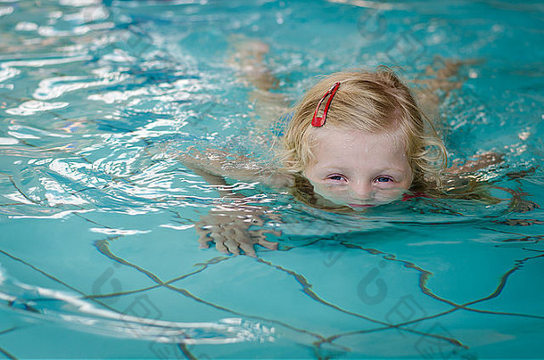 可爱的金发女孩沉浸在游泳池里的水里
