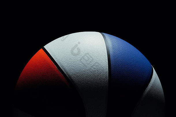 红色、白色和蓝色美国单色篮球的前视图，位于黑色背景上。光线直接照射在篮球上。戏剧灯光