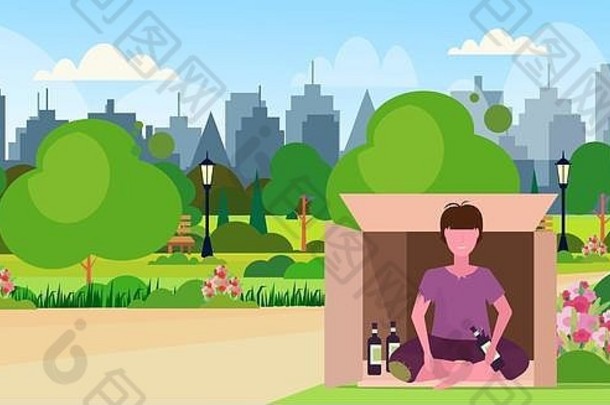 悲伤的男人醉酒的乞丐坐在户外的纸箱里，手里拿着一瓶酒无家可归失业概念城市公园城市景观
