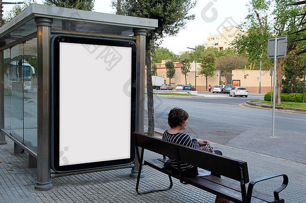 公共汽车站的空白广告牌上，一位年轻女子坐在长凳上