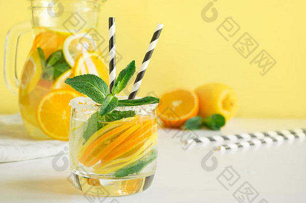 新鲜的夏日柠檬水，柠檬、橘子、薄荷和冰，黄色背景。闭合。复制空间。