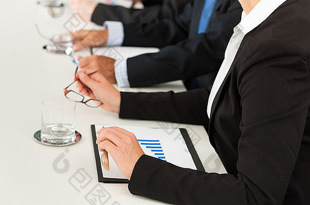 商务-人们坐在一个会议上，特写镜头在手上，女人在前面