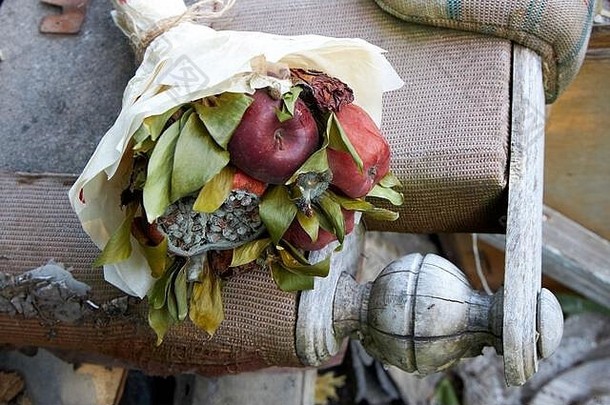 一束腐烂的水果和枯萎的花朵躺在旧家具的残骸上