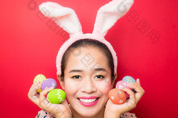 女人穿兔子耳朵头巾携带复活节鸡蛋复活节季节有吸引力的年轻的女人微笑明亮的红色的背景