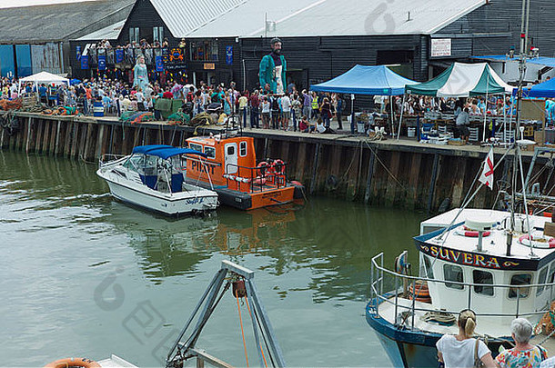 维特斯塔布尔牡蛎节上，巨人们沿着港口行进，许多旁观者都在观看