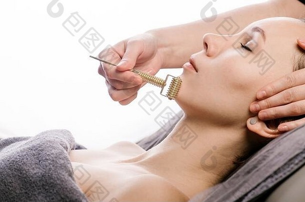 在美容诊所进行刮痧面部按摩时，滑动压路机抵住下巴。