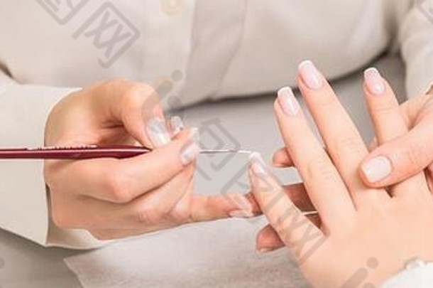 手年轻的女人接收法国修指甲美容师指甲沙龙