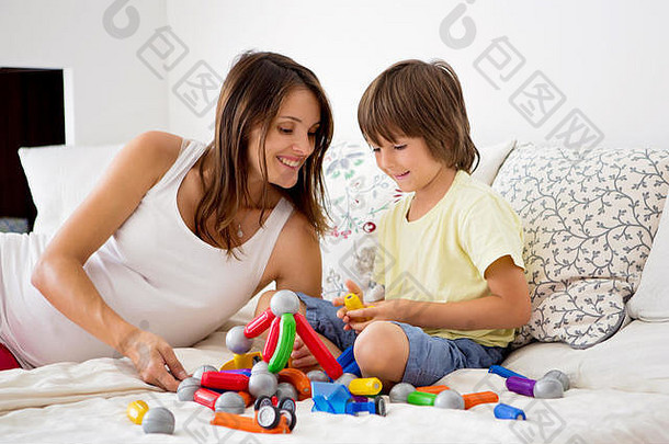 可爱的怀孕妈妈和小男孩在家里玩玩具