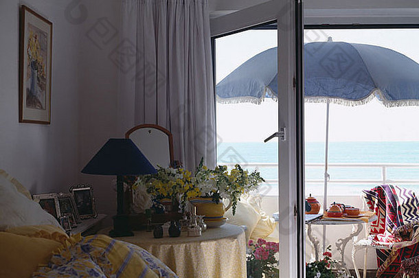从卧室天井的阳伞门看去，阳台上有桌子和椅子，可以看到大海