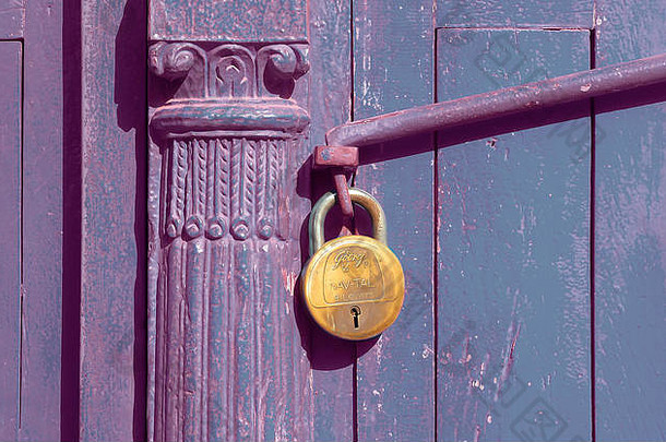 黄铜挂锁锁住紫色木门或大门