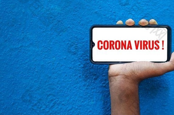 科罗娜啤酒病毒2019冠状病毒疾病病毒在智能手机屏幕上的蓝色背景下，文本空间。手上拿着手机并展示的人