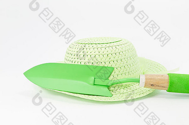 浅绿色草帽，绿色木抹子和白色背景上的绿色软垫把手
