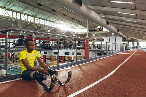 残疾的非洲裔美国男子运动员坐在健身中心的跑道上