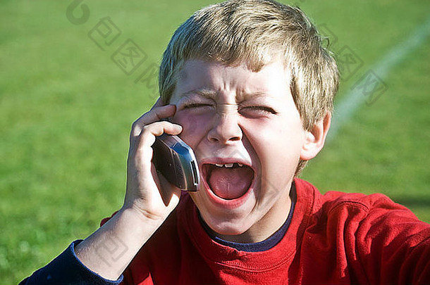 一个张大嘴巴的男孩，对着手机不是笑就是喊。