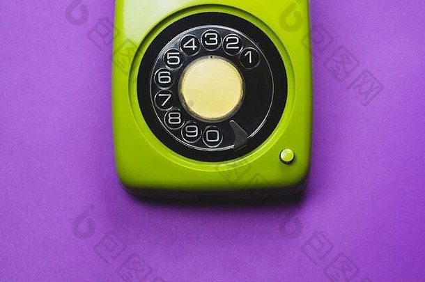 老式旋转电话。经典的绿色圆形拨号电话。在紫色背景上分离。旧的通讯技术。拷贝空间