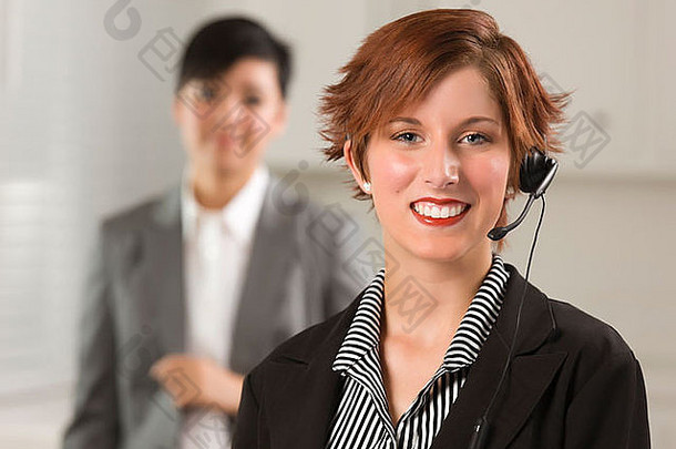 漂亮的红发女商人和同事，在办公室戴着耳机。