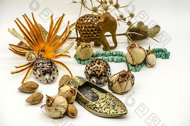 古代东方纪念品，绿松石珠子，木制大象雕像，烟灰缸形状的黄铜拖鞋，干芽，刺，白背上的贝壳