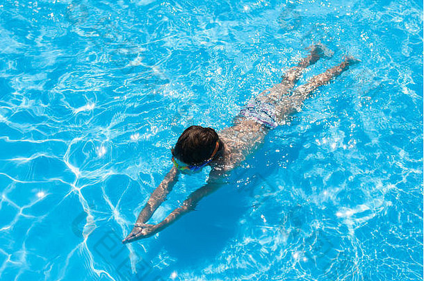 夏天，健康的白人小孩戴着护目镜在淡水蓝池里潜水
