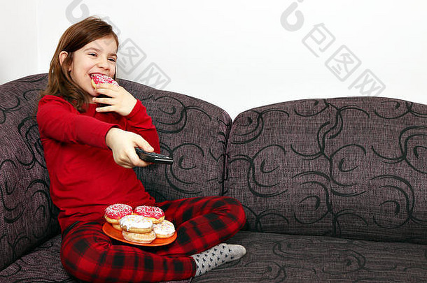 快乐的小女孩看电视吃甜甜圈