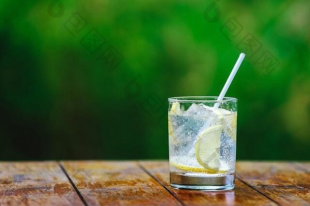玻璃。柠檬加冰块的矿泉水。鸡尾酒吸管。绿色背景绿色背景