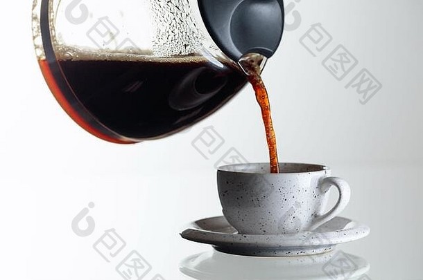 玻璃桌上的陶瓷杯中的黑咖啡。咖啡从咖啡机倒进杯子里。空间。