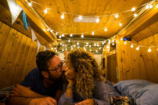 旅行和浪漫之夜，在一辆木制修复的漂亮面包车内，为相爱的快乐成年白人夫妇放松身心，彼此亲吻——漫游癖a