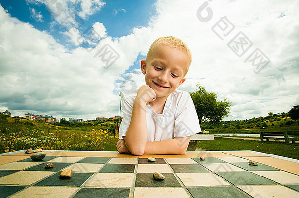 国际跳棋董事会游戏男孩聪明的孩子孩子玩跳棋思考户外公园童年发展
