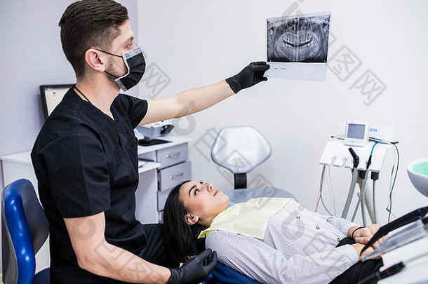 牙医在牙科诊所看年轻女病人的牙齿x光片