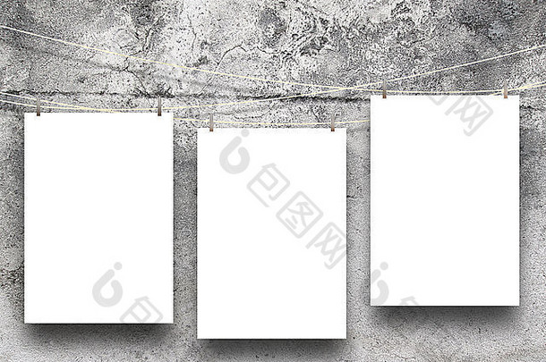 在灰色混凝土墙背景上用衣夹悬挂的三个纸框架的特写