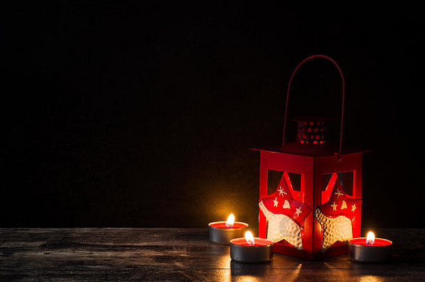 木制桌子上的红色圣诞灯笼和蜡烛。拷贝空间