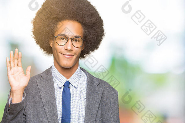 年轻的非洲裔美国商人戴着眼镜，留着非洲裔头发，面带微笑地说“你好”，友好的欢迎手势