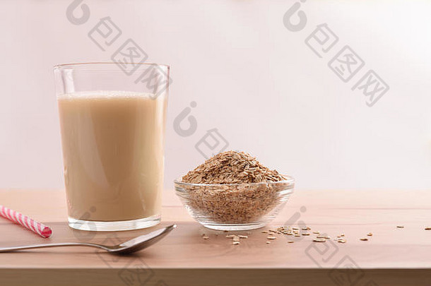玻璃燕麦饮料和白色背景的厨房长凳上的麦片。水平构图。前视图