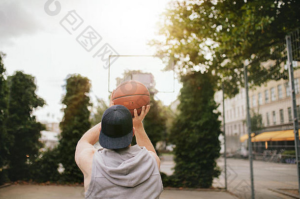 后视图拍摄年轻的的家伙玩篮球户外法院街头篮球球员芽篮子