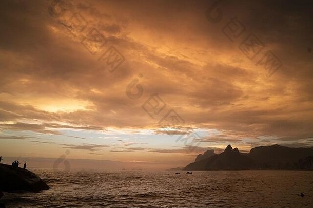 里约热内卢伊帕内马海滩上的壮观日<strong>落</strong>，<strong>金</strong>色的<strong>光线</strong>照射在灰色的云层上。