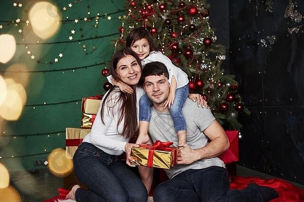 摆姿势拍照。冬夜，可爱的一家人坐在<strong>圣诞</strong>树旁，手里拿着礼品盒，享受着<strong>一起</strong>度<strong>过</strong>的时光