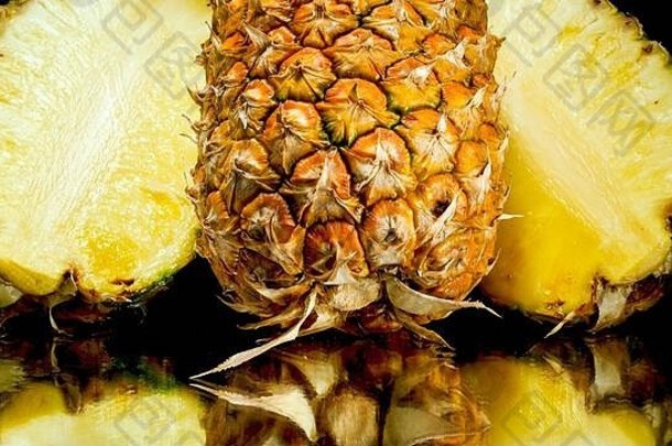 切好的菠萝一半放在黑色背景上的特写图片。外来热带水果的抽象背景。