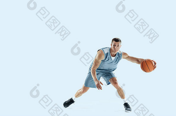 对……充满激情。年轻的白种人篮球队员在比赛中，在蓝色背景上孤立地跳起。运动、运动、活力和健康生活方式的概念。训练，练习。
