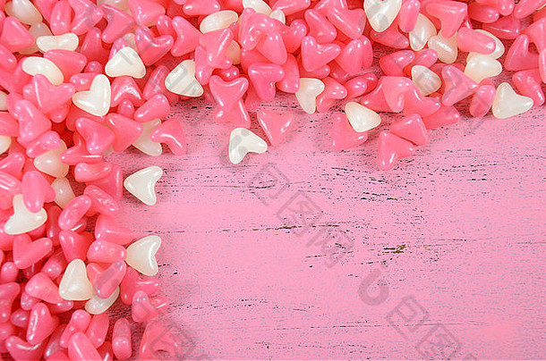 粉色和白色心形果冻糖糖果，以粉色木材为背景，并在此处留有文本空间。