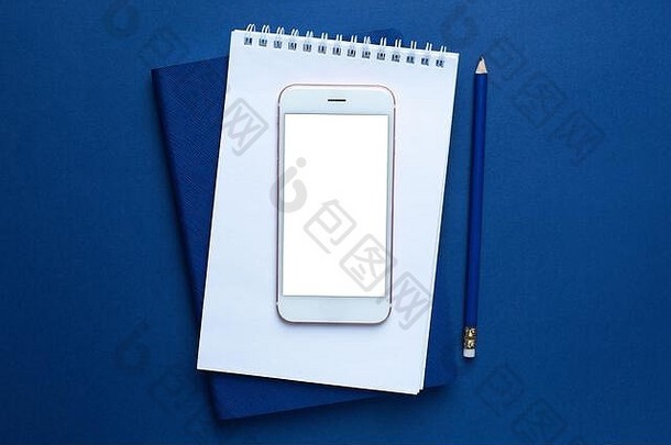 移动电话白色蓝色的办公室笔记本铅笔经典蓝色的背景前视图时尚的颜色