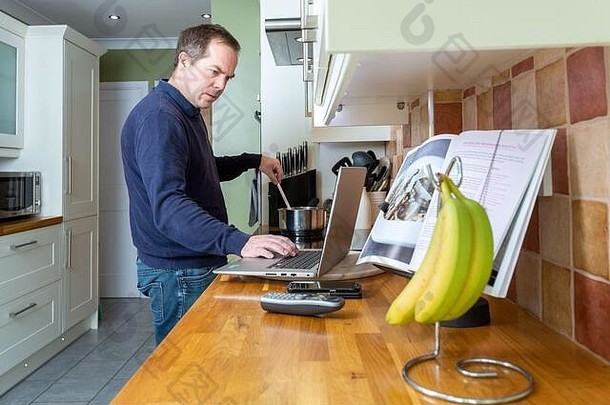 在CVID-19冠状病毒大流行隔离封锁期间压力下在家工作的悲惨男子在厨房工作