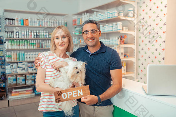 企业家持有白色狗开放宠物商店