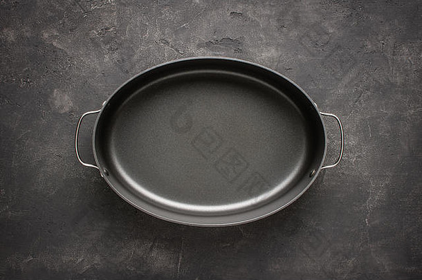 空的灰色不粘烘焙盘，手柄位于深色石头表面。烹饪背景。
