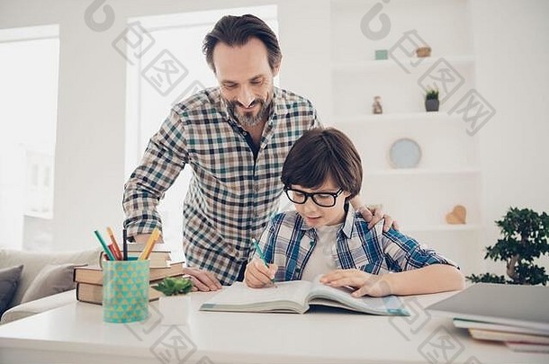 用最好的方法研究学科概念。聪明、耐心、聪明、成熟的爸爸帮助儿子准备家庭作业和考试的照片